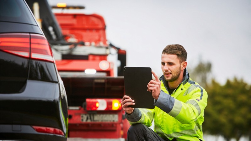 A tow truck driver shoots a picture with his tablet.